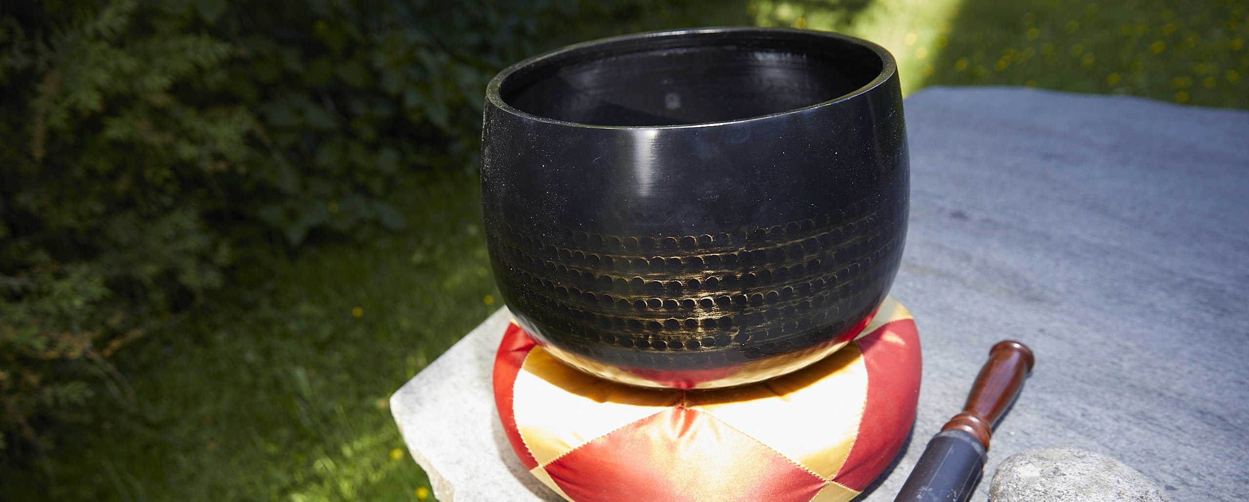 Eine schwarze Klangschale steht auf einem orangen Kissen.